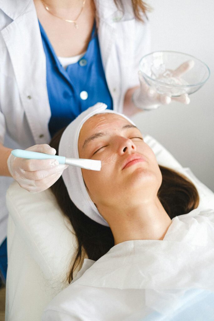 From above of a staff member putting moisturizing lotion on face during beauty procedure